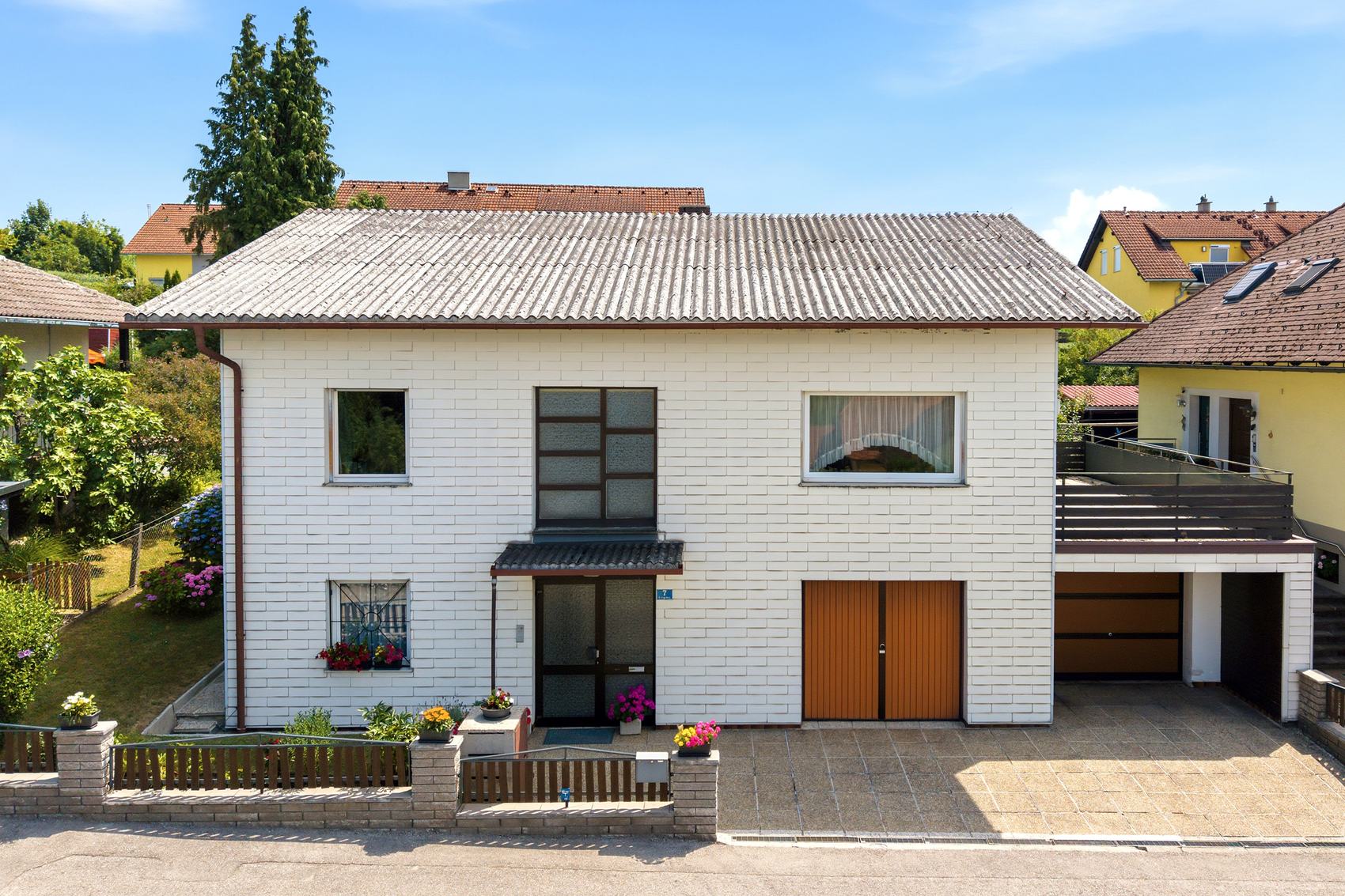 Weißes Einfamilienhaus mit Garage und Vorgarten