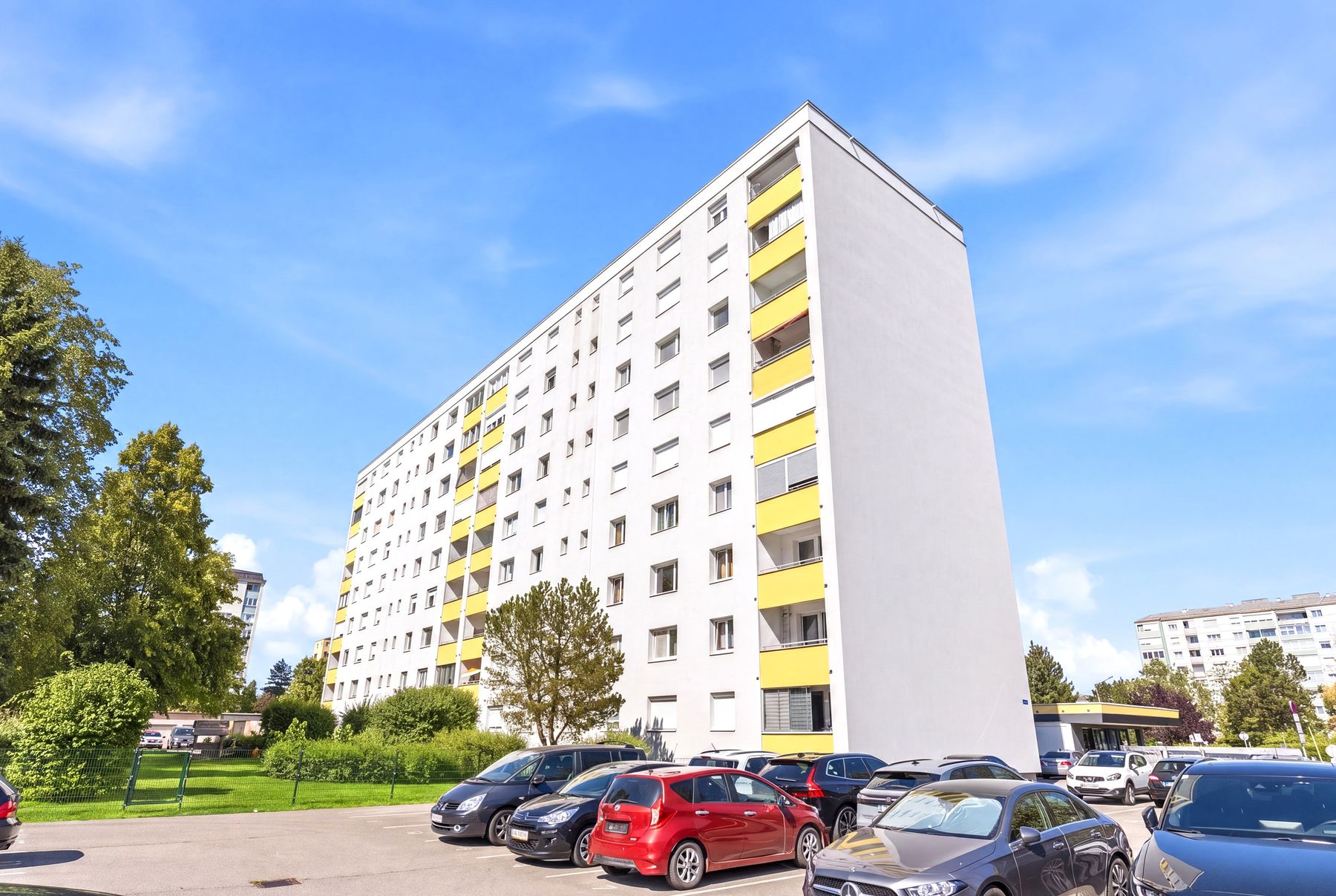 Hochhaus mit gelber Fassade und Parkplatz