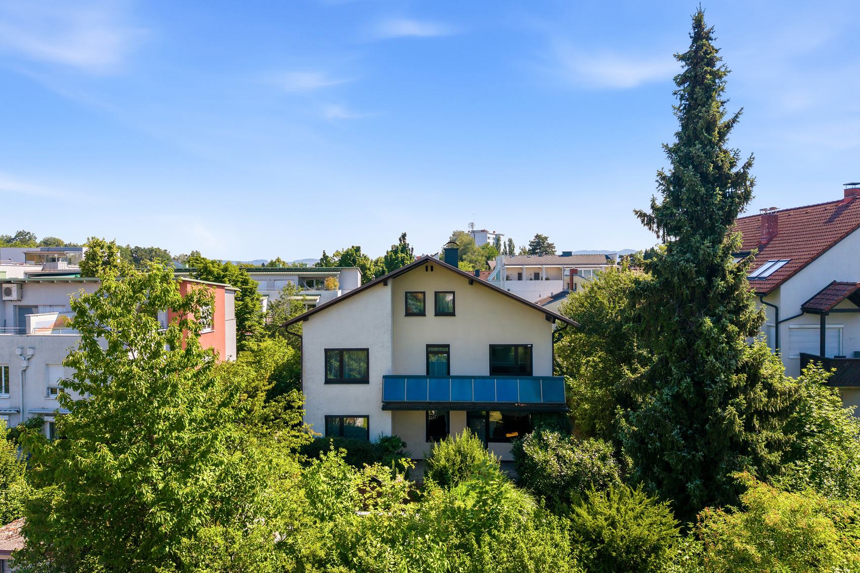 Einfamilienhaus mit Balkon zwischen hohen Bäumen