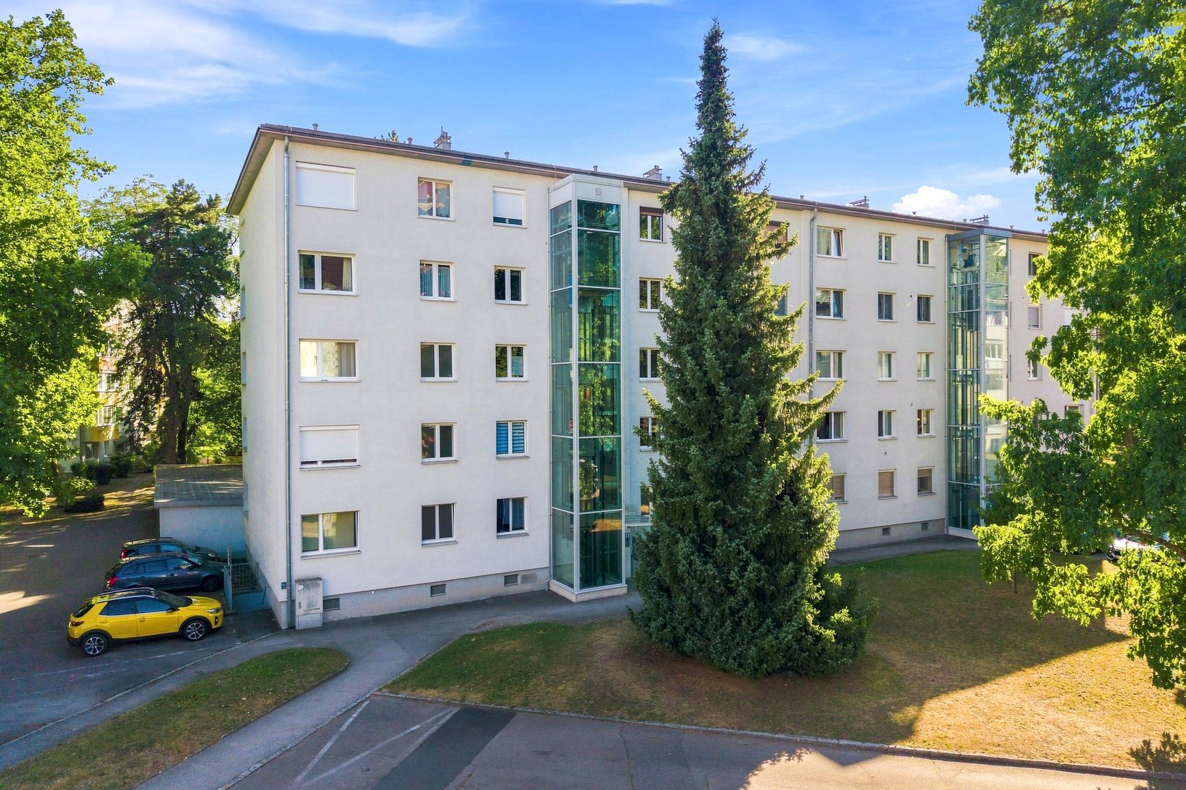 Wohnblock mit Balkonen zwischen hohen Bäumen
