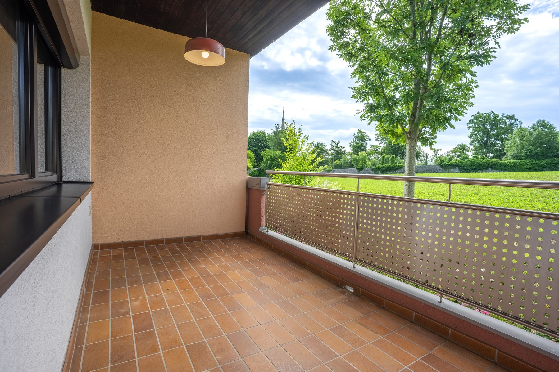 Balkon mit Blick auf eine Wiese mit Bäumen