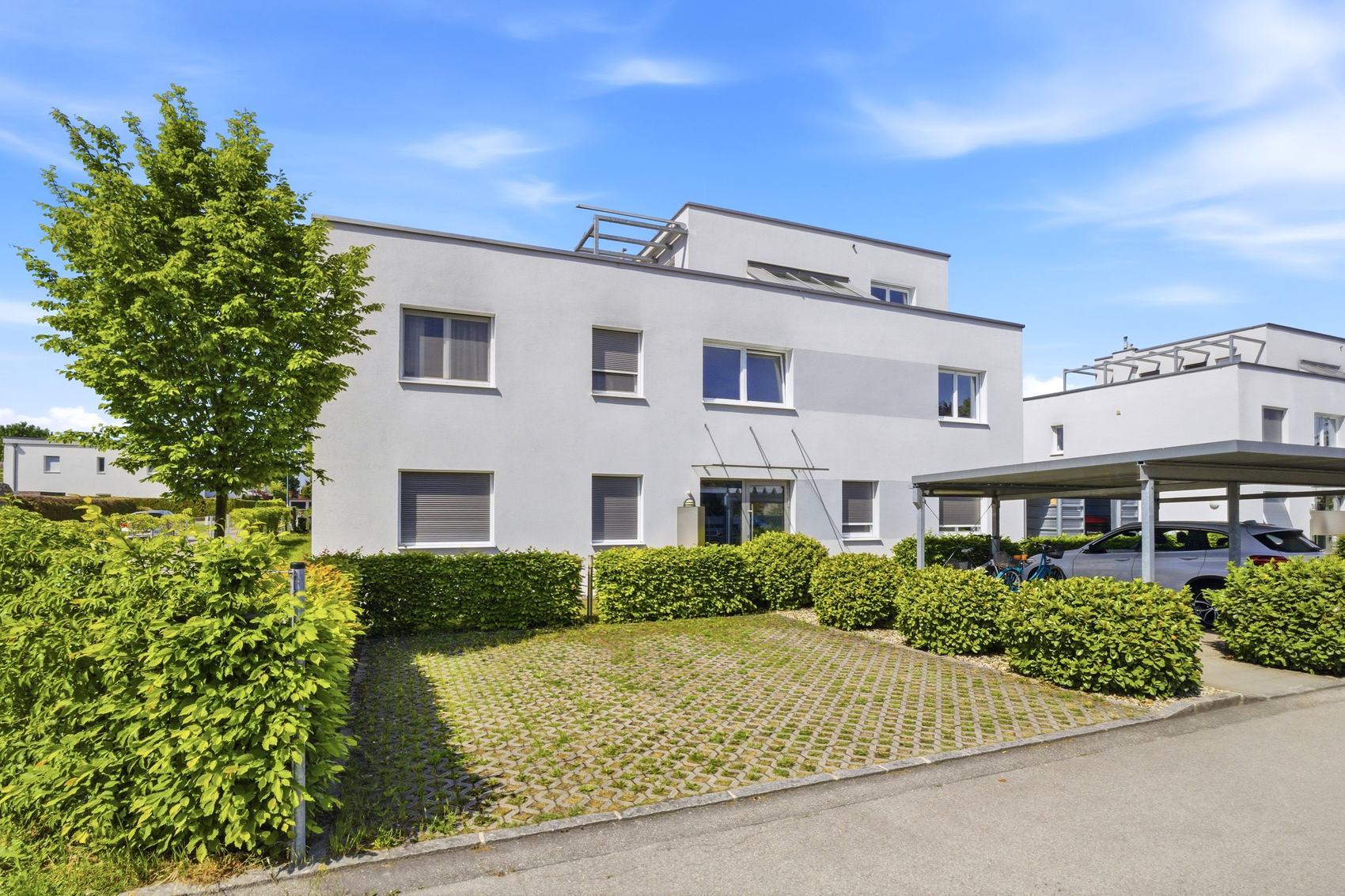 Moderner weißer Neubau mit Carport und Vorgarten