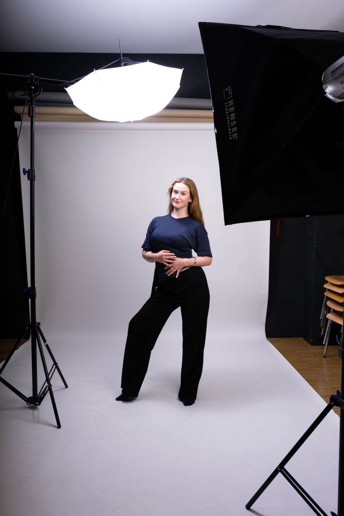 Blick ins Fotostudio: Model vor weißem Hintergrund zwischen Schirm- und Softbox-Licht